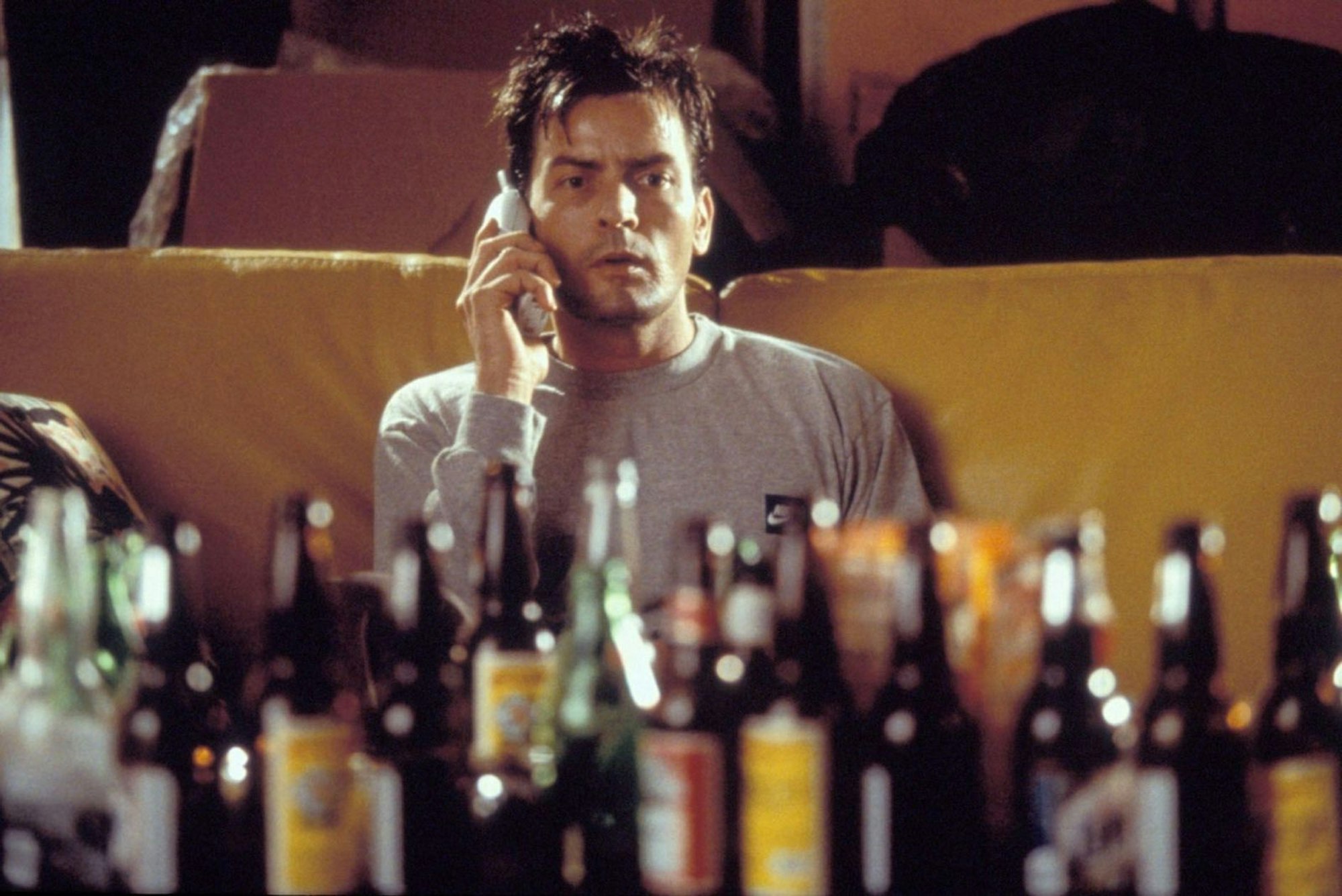 Ein Symbolbild aus dem Film „Good Advice“ von 2001: Charlie Sheen sitzt vor einer Reihe leerer Alkoholflaschen. (Bild: RTL II)