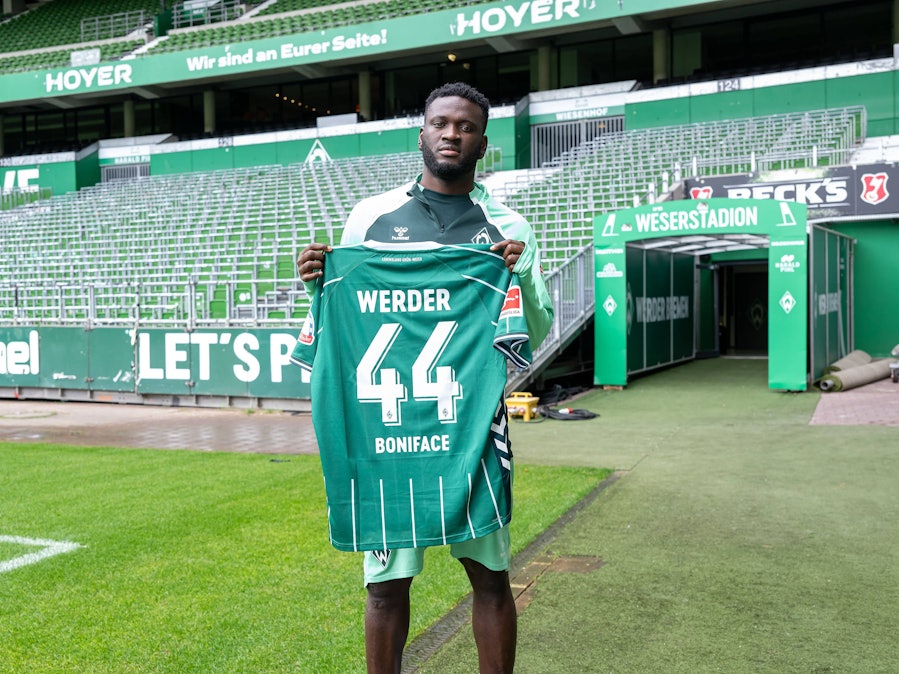 Victor Boniface hält sein neues Trikot vom SV Werder Bremen.