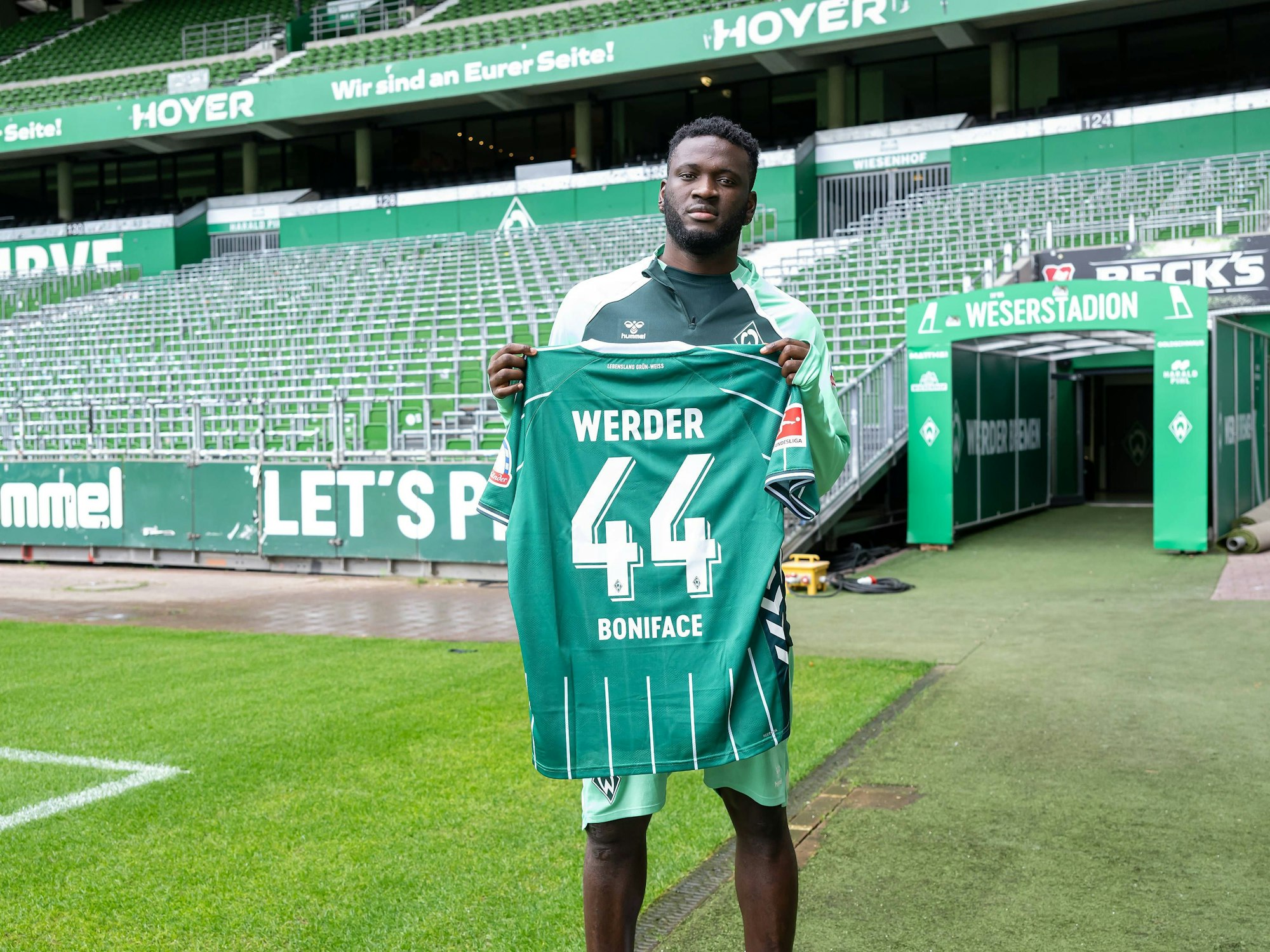 Victor Boniface hält sein neues Trikot vom SV Werder Bremen.