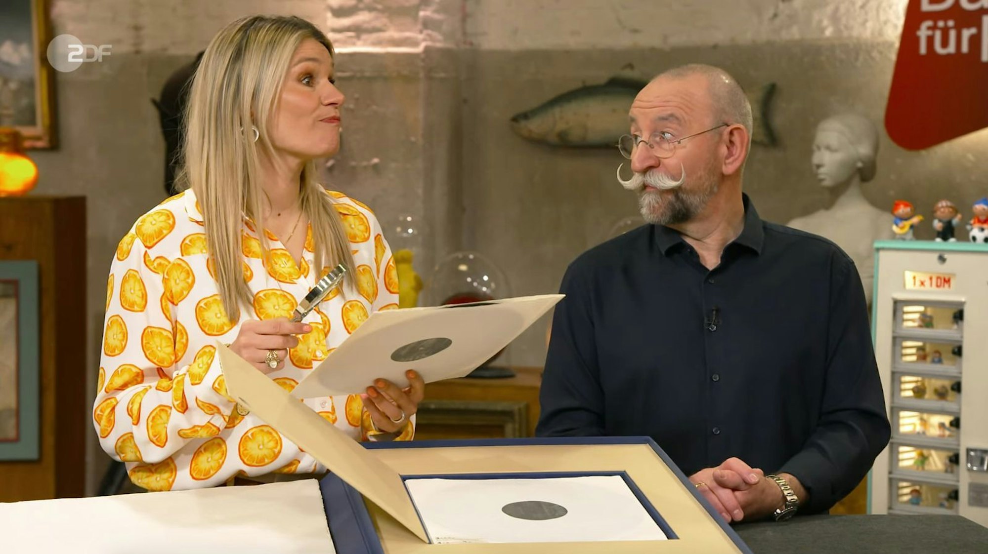 Horst Lichter und Bianca Berding waren gleichermaßen begeistert von einer Mappe mit Grafik und Musik zu Ehren von Louis Armstrong. (Bild: ZDF)