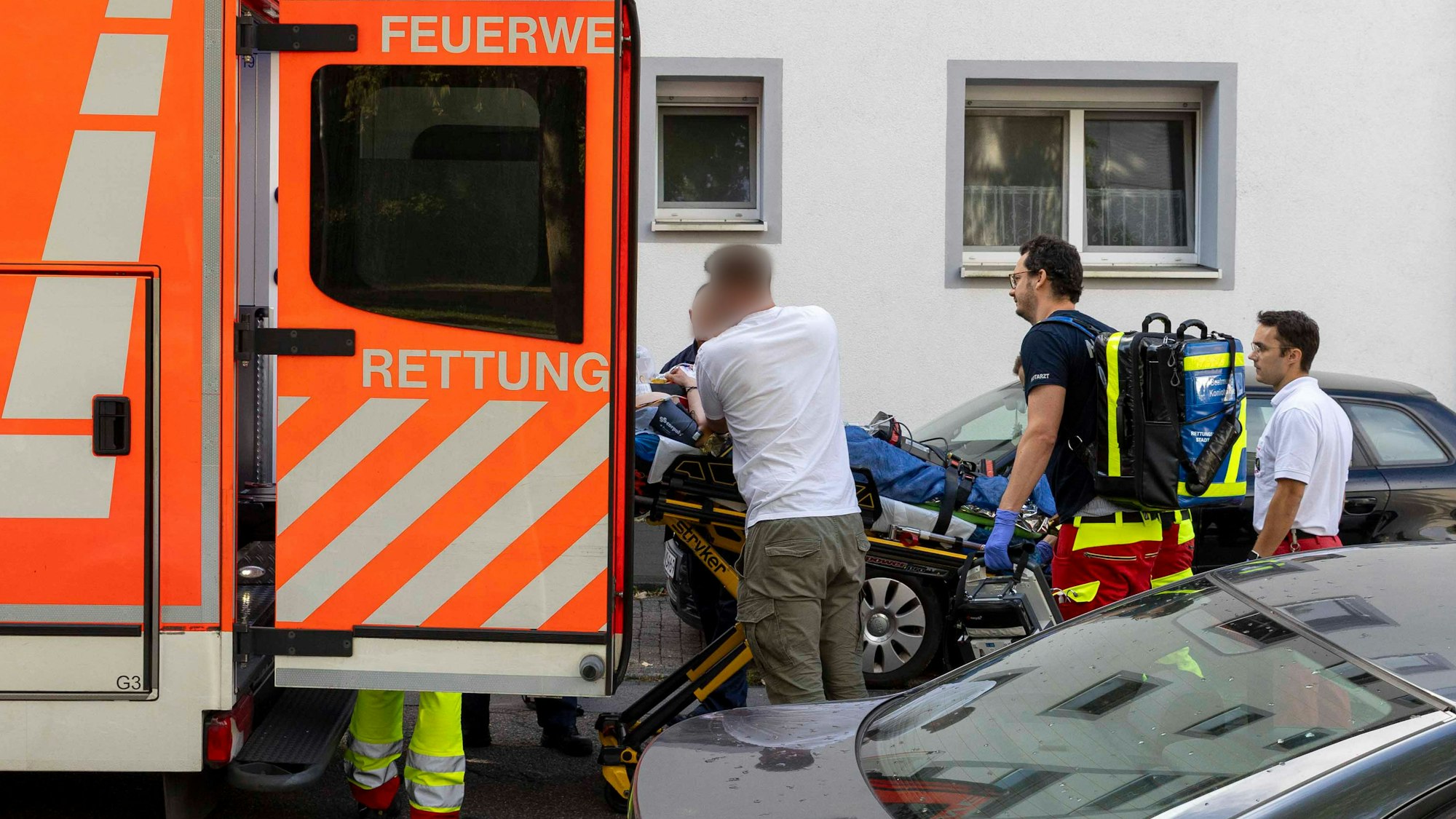 Eine verletzte Person wird an einem Berufskolleg in Essen zu einem Rettungswagen gebracht. An dem Berufskolleg ist eine Lehrerin von einem Täter mit einem Messer attackiert und verletzt worden.