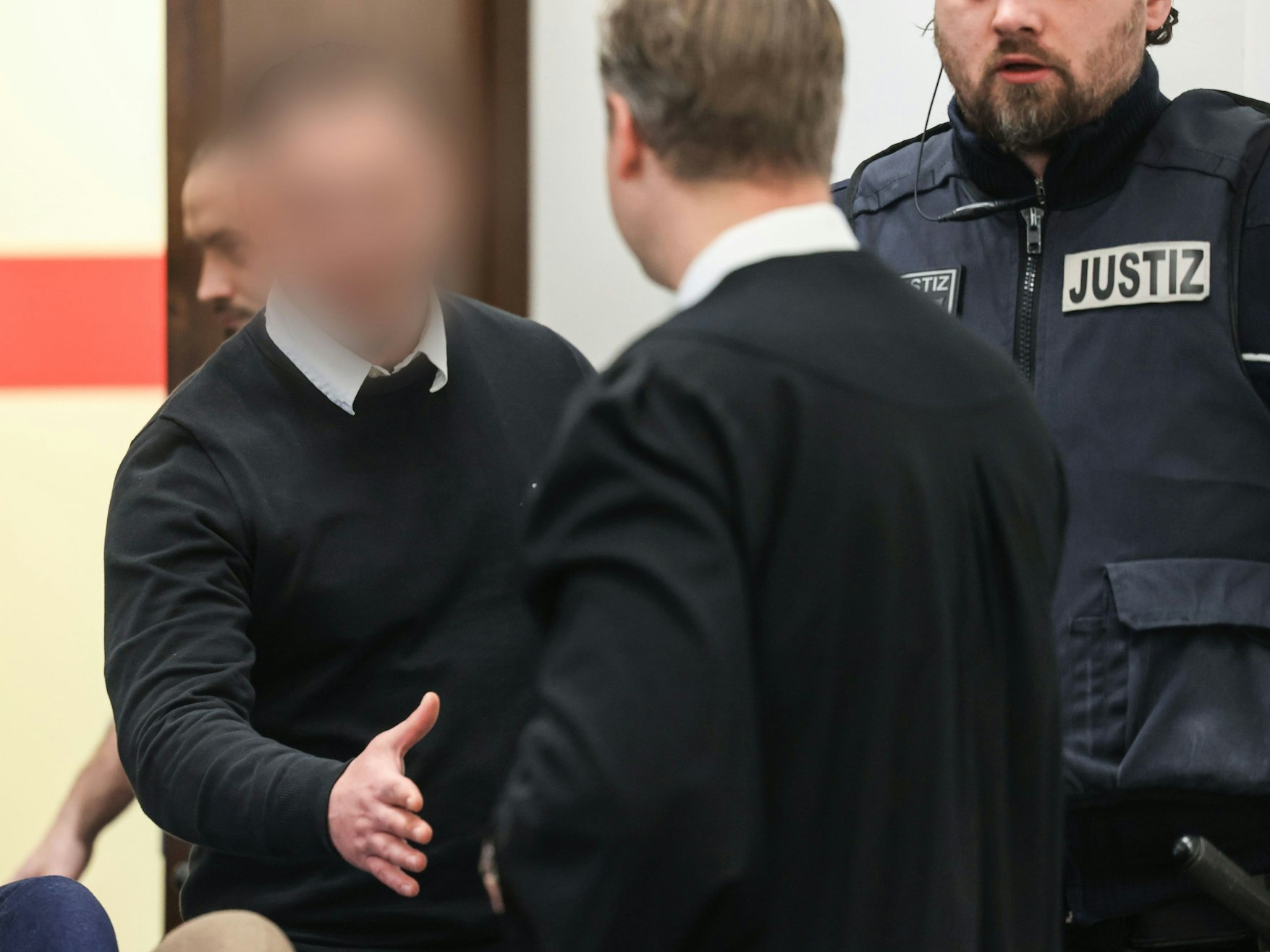 Der 28-jährige Angeklagte begrüßt seinen Verteidiger beim Prozessauftakt im Landgericht Köln.