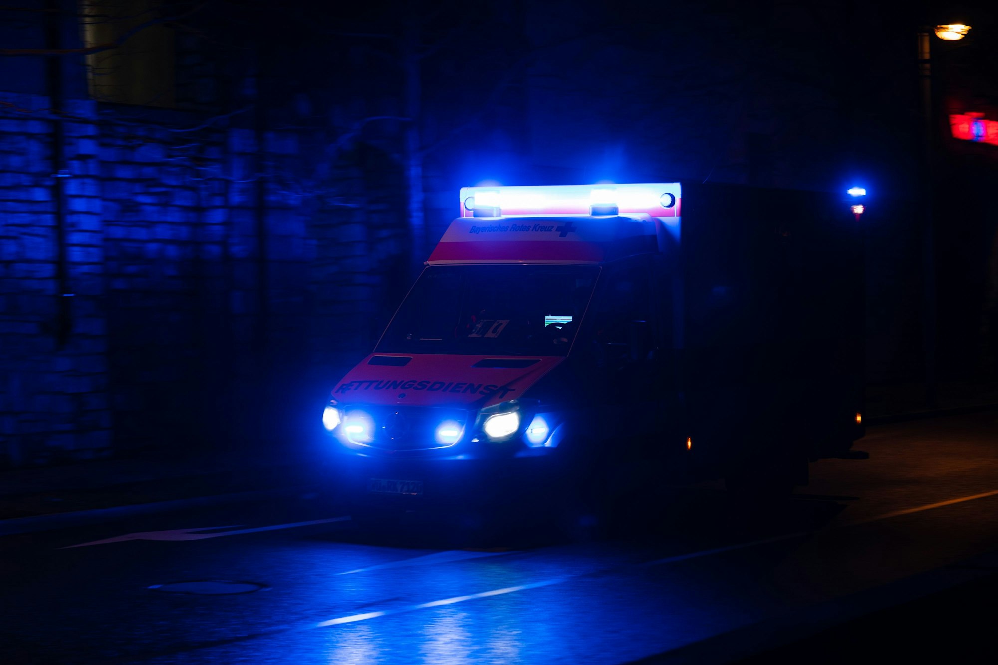 Ein Krankenwagen fährt nachts mit Blaulicht durch eine Straße. (Symbolfoto)