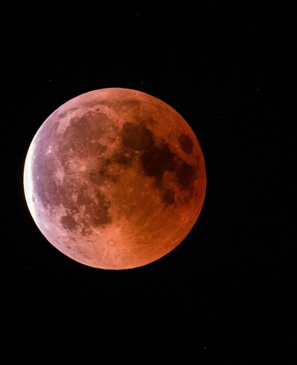 Der teilweise vom Erdschatten verdunkelte Vollmond leuchtet während einer Mondfinsternis rötlich.