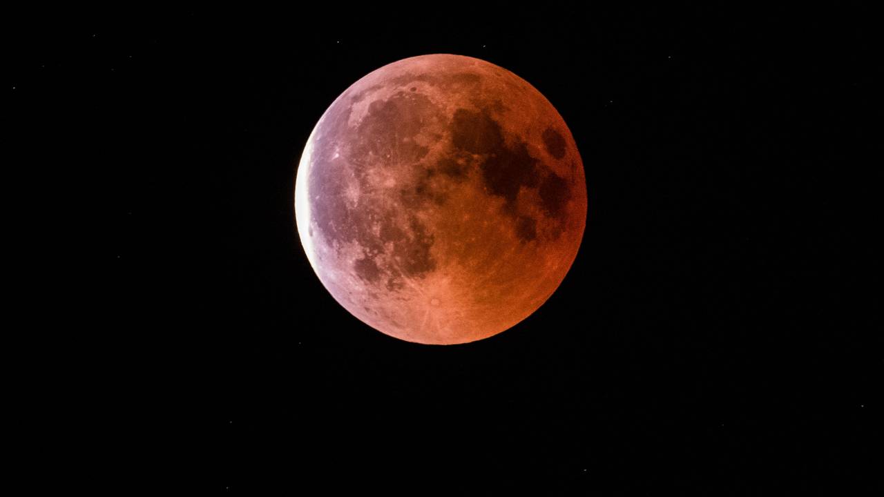 Der teilweise vom Erdschatten verdunkelte Vollmond leuchtet während einer Mondfinsternis rötlich.