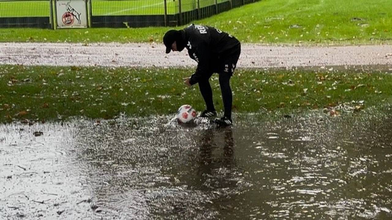 FC-Torwarttrainer Peter Greiber holt einen Ball aus einer Pfütze.