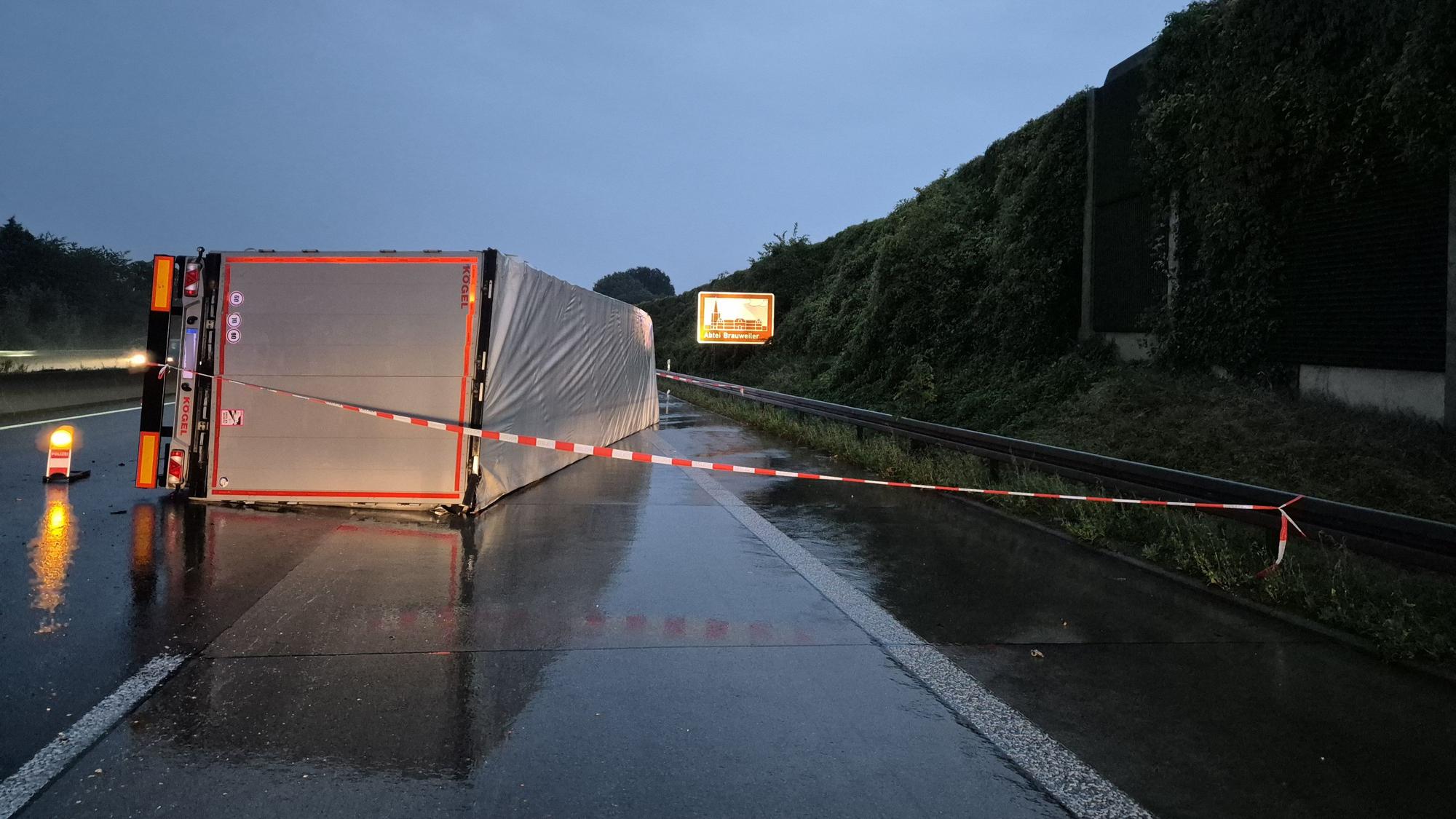 Ein LKW liegt auf der regennassen Fahrbahn.