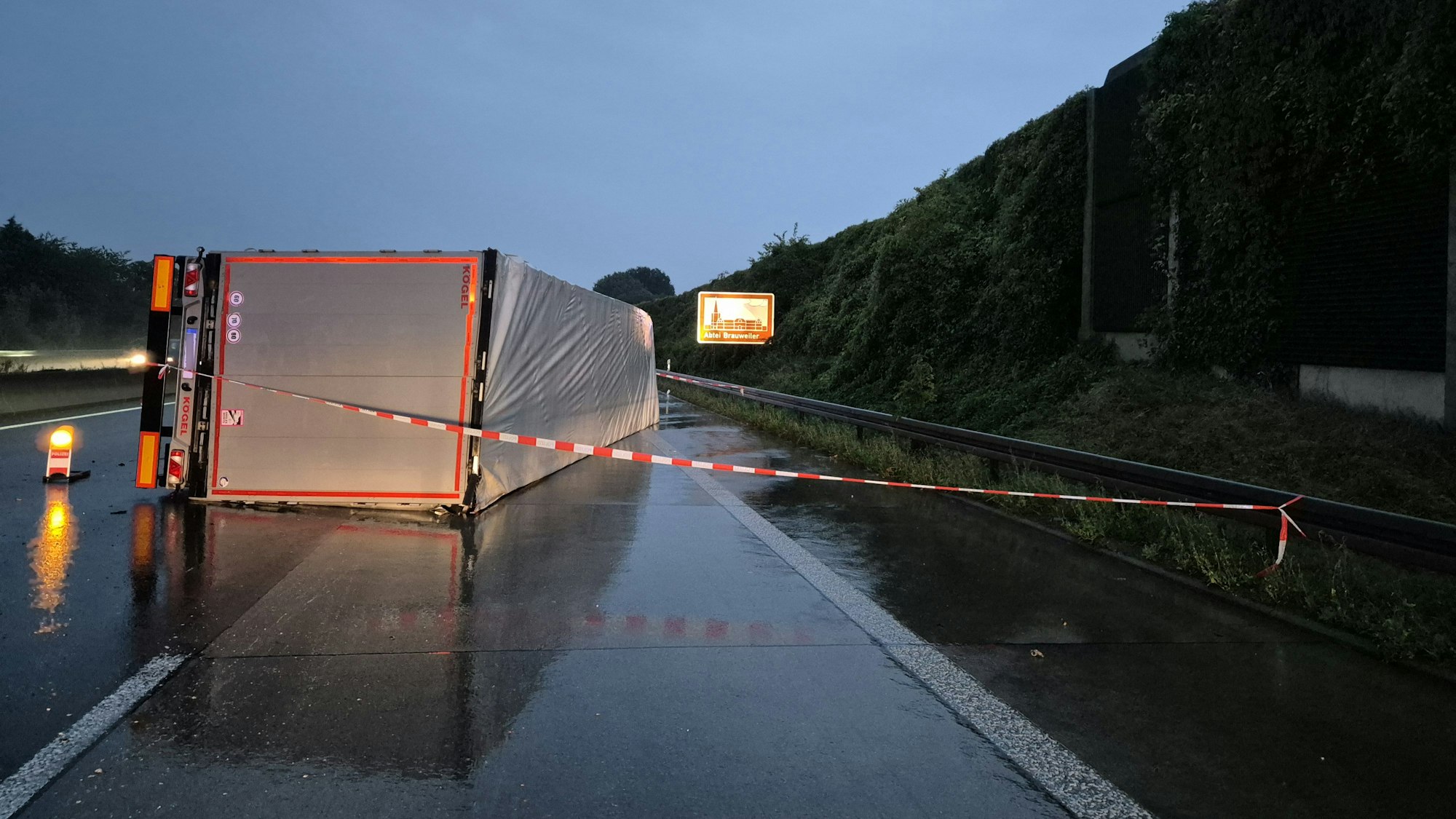 Ein LKW liegt auf der regennassen Fahrbahn.