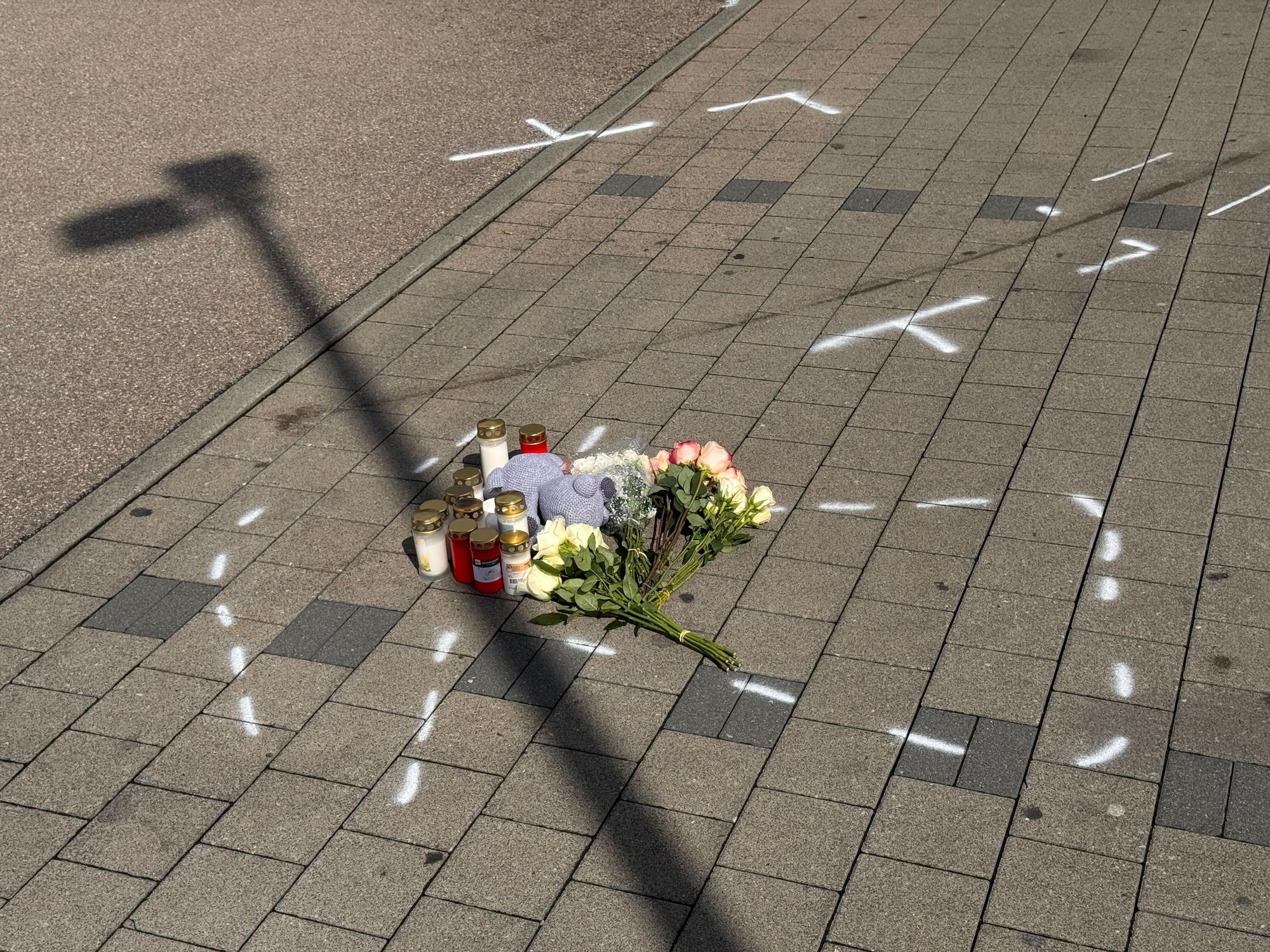 Markierungen mit Sprühfarben und Trauerbekundungen sind auf einem Parkplatz zu sehen. Nach einem Streit auf einem Parkplatz soll ein 18-Jähriger einen 12 Jahre alten Jungen in Niedernhall (Hohenlohekreis) mit dem Auto verfolgt, angefahren und tödlich verletzt haben.