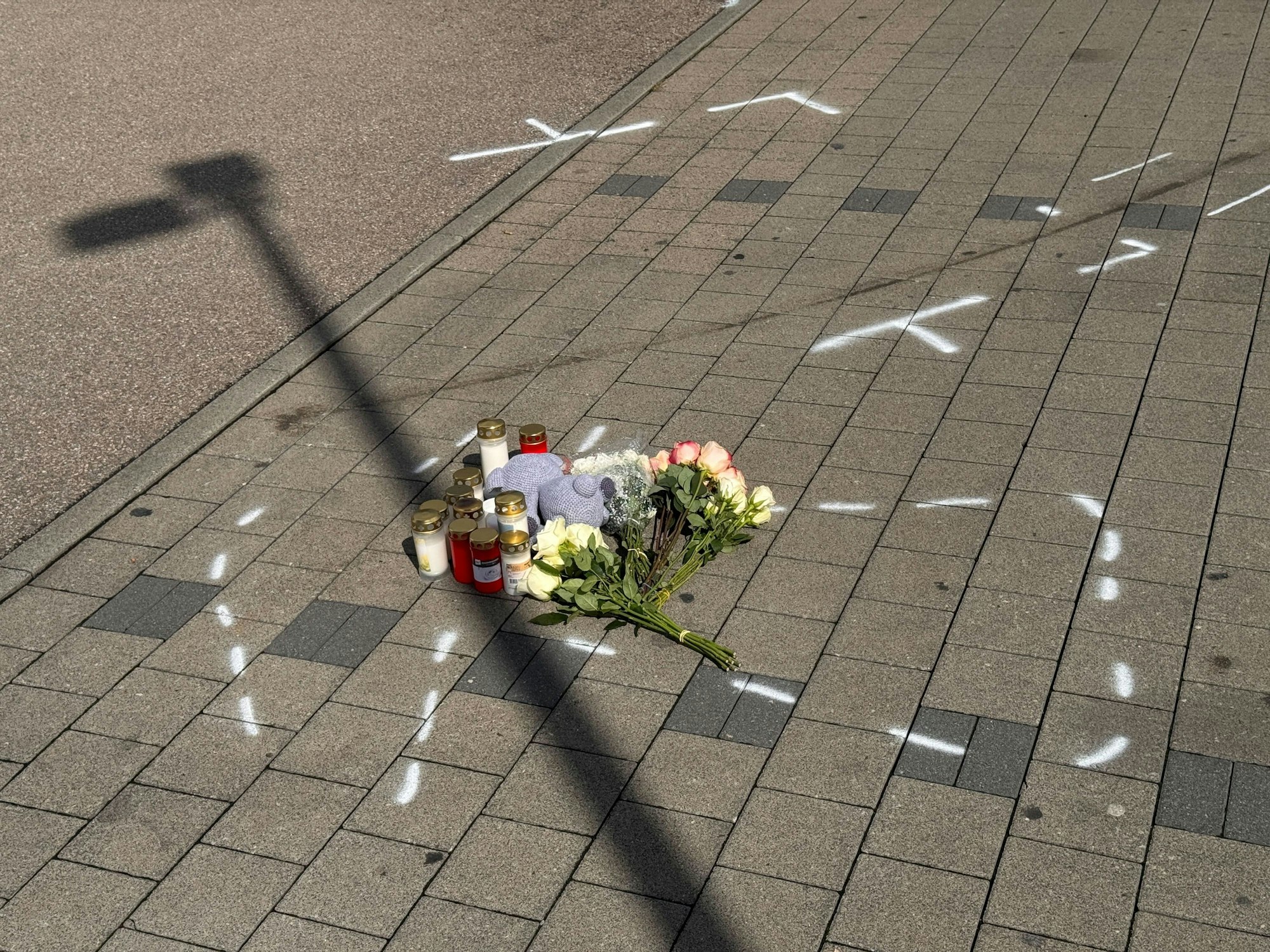 Markierungen mit Sprühfarben und Trauerbekundungen sind auf einem Parkplatz zu sehen. Nach einem Streit auf einem Parkplatz soll ein 18-Jähriger einen 12 Jahre alten Jungen in Niedernhall (Hohenlohekreis) mit dem Auto verfolgt, angefahren und tödlich verletzt haben.