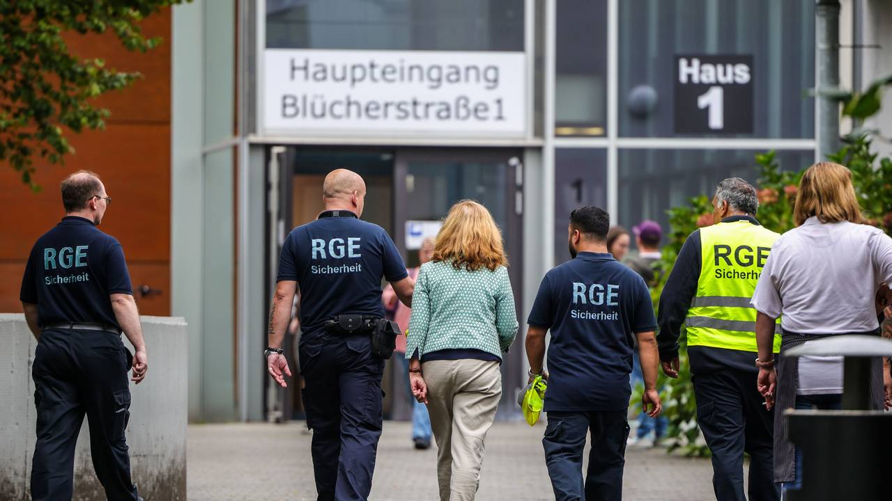 Mehrere Mitarbeiter der Schule und eines Sicherheitsunternehmens gehen auf dem Gelände der Schule, in der ein Angriff auf eine Lehrerin stattgefunden hat.