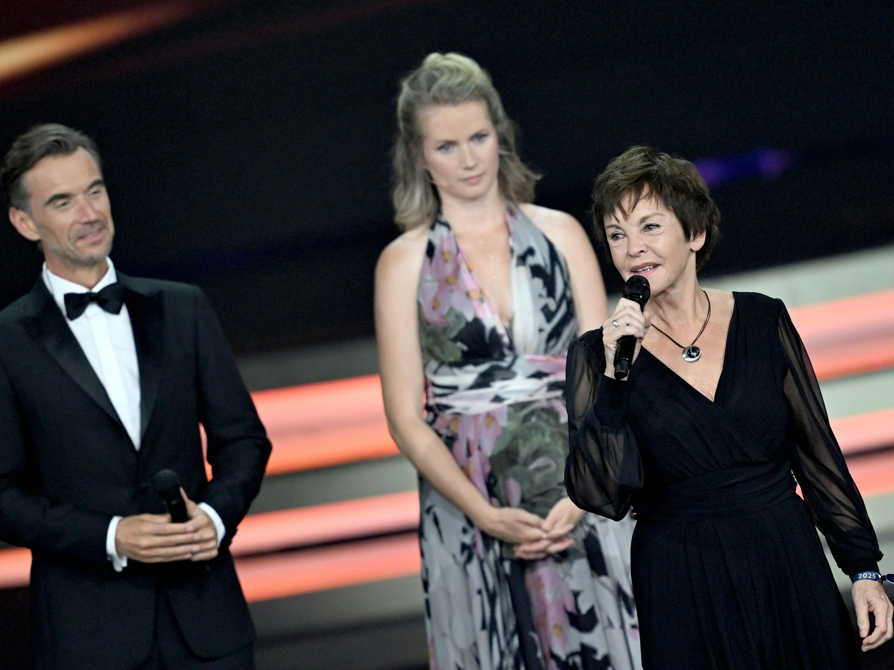 Die Schauspielerin Katrin Sass (vorn) bedankt sich bei der Verleihung des Medienpreises Goldene Henne vor Laudatorin und Schauspielerin Cornelia Gröschel und Moderator Florian Silbereisen über den Ehrenpreis.