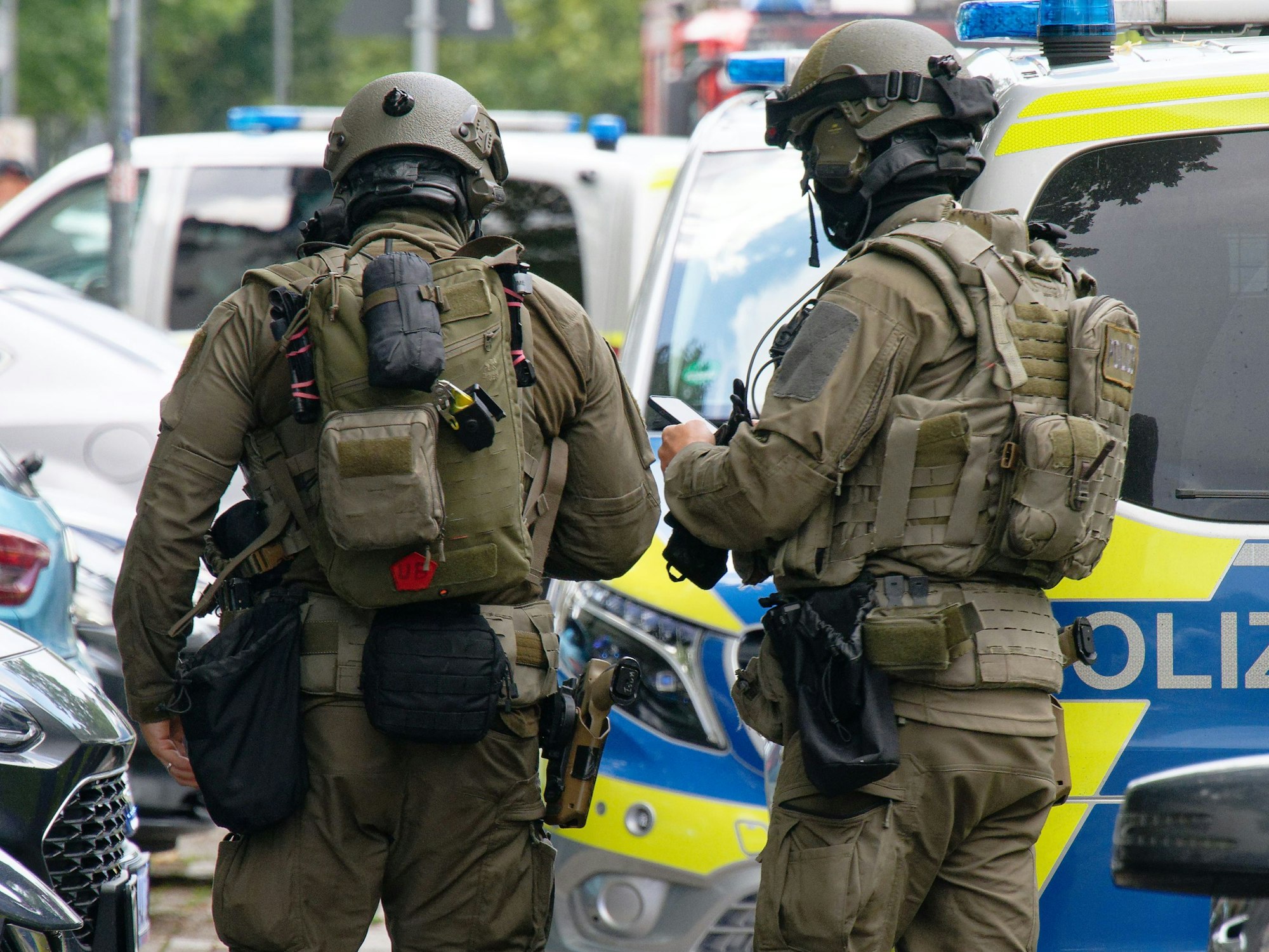 Zwei SEK-Kräfte stehen vor einem Polizeifahrzeug.