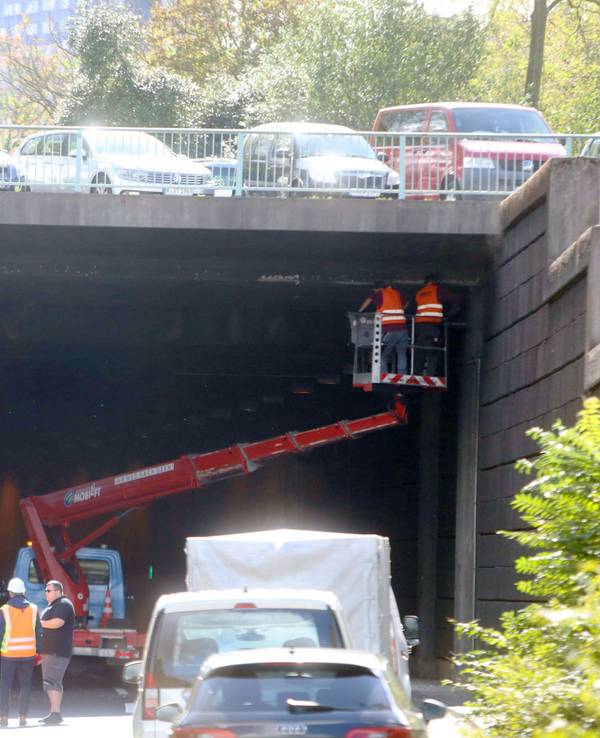 Zwei Personen stehen auf einer Hebebühne und untersuchen die Decke eines Tunnels.