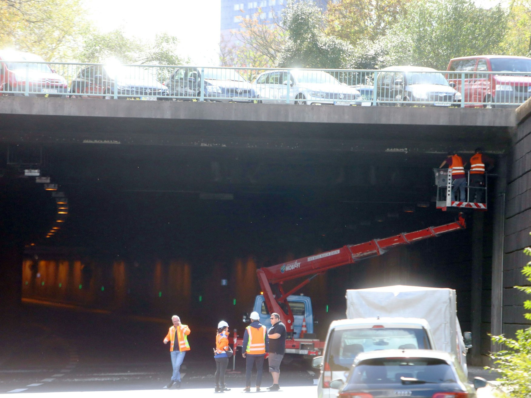 Zwei Personen stehen auf einer Hebebühne und untersuchen die Decke eines Tunnels.