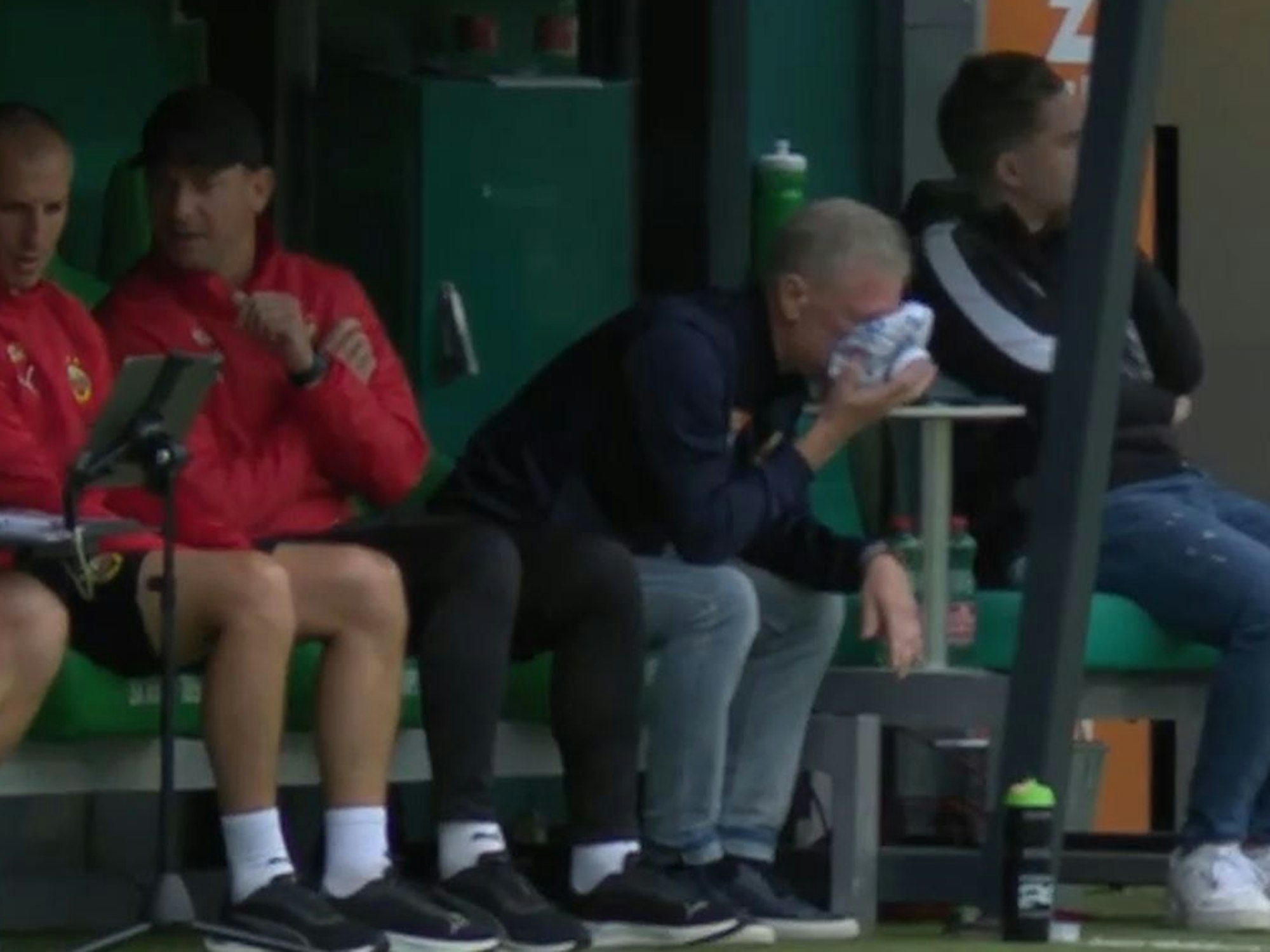 Peter Stöger mit einem Eisbeutel auf dem Gesicht auf der Trainerbank.