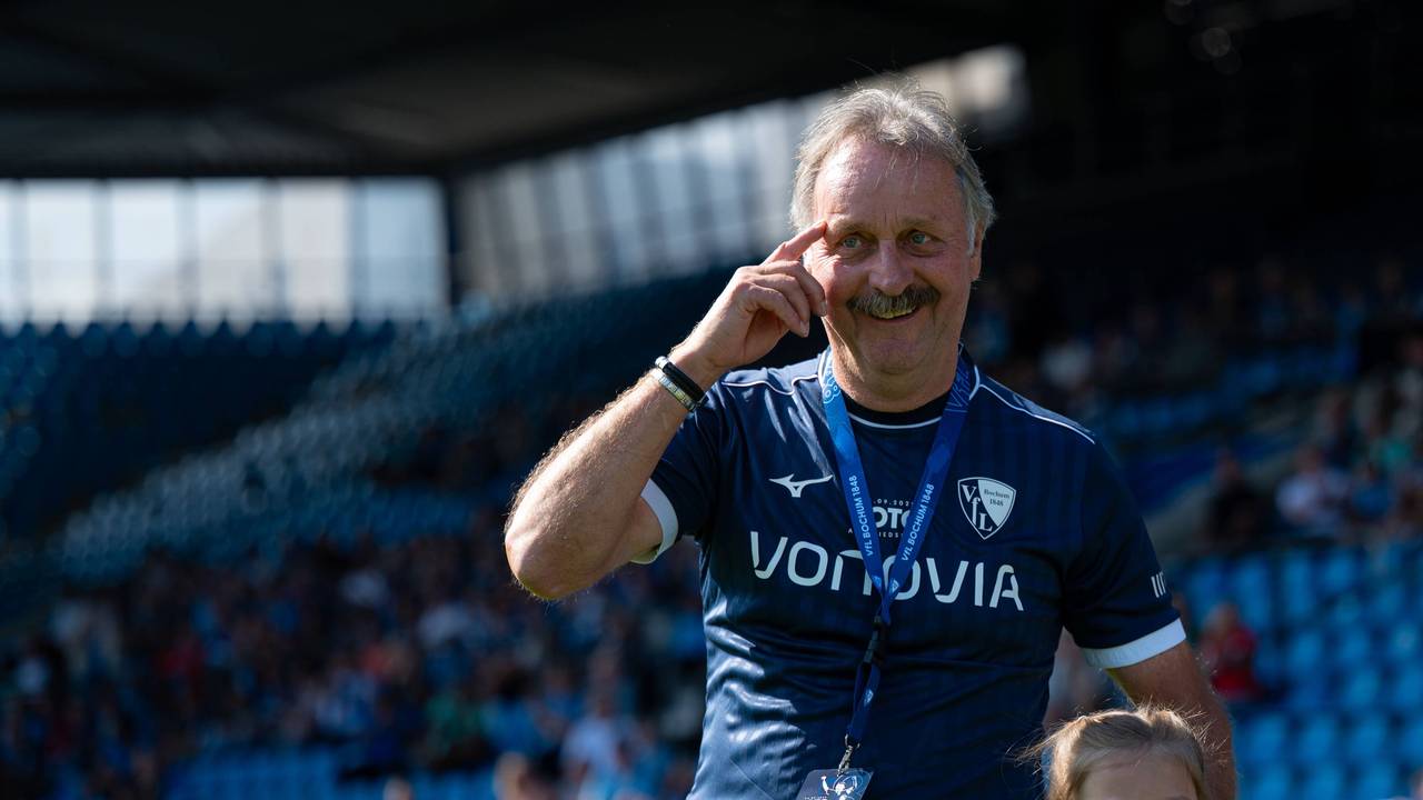 Peter Neururer trägt ein Trikot des VfL Bochum und fasst sich mit dem rechten Zeigefinger an seine Augenbraue.