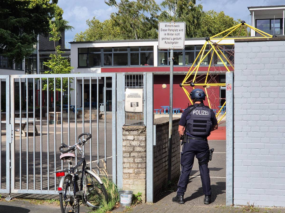 Ein Polizist steht vor einer Schule.