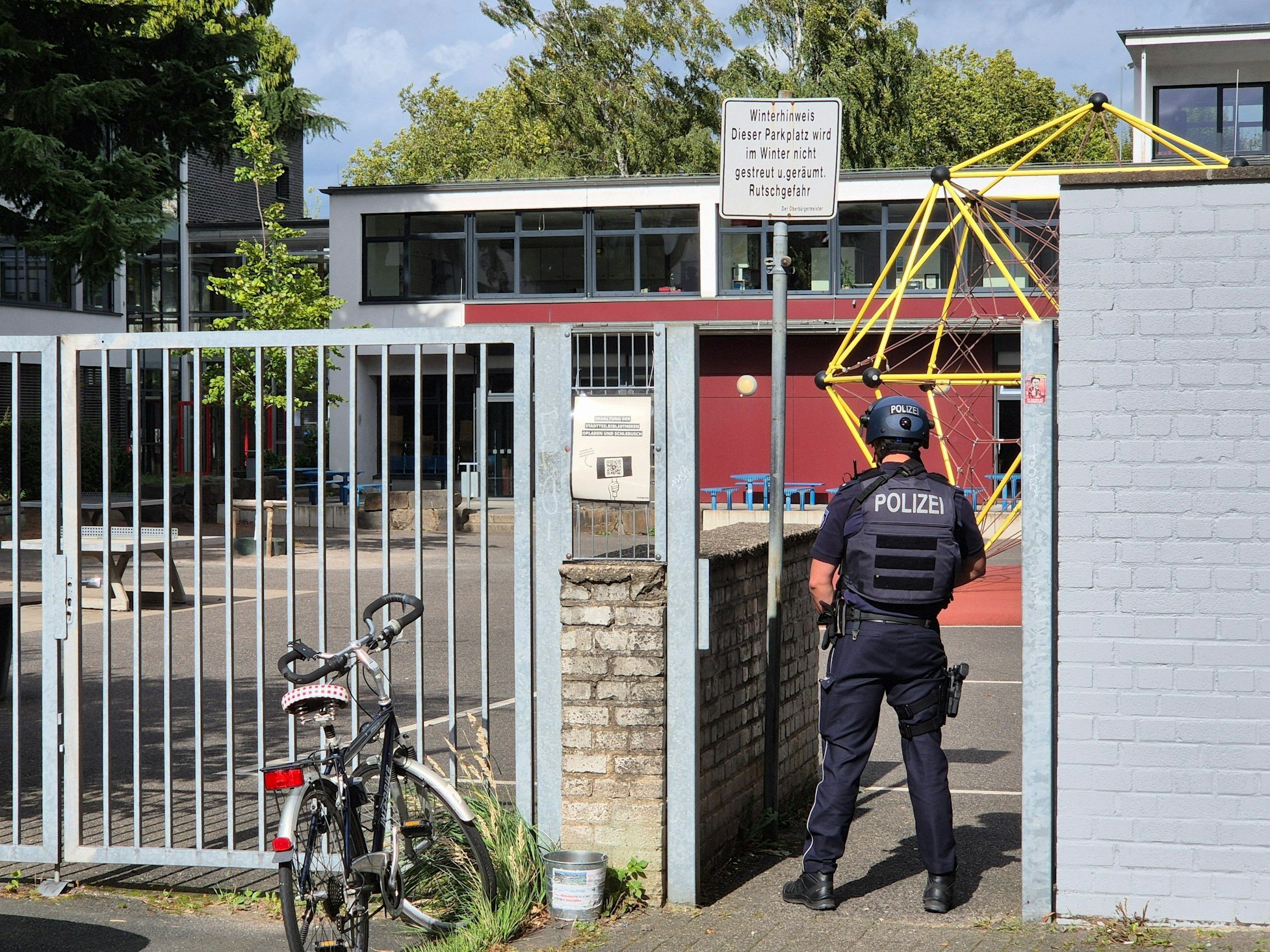 Ein Polizist steht vor einer Schule.