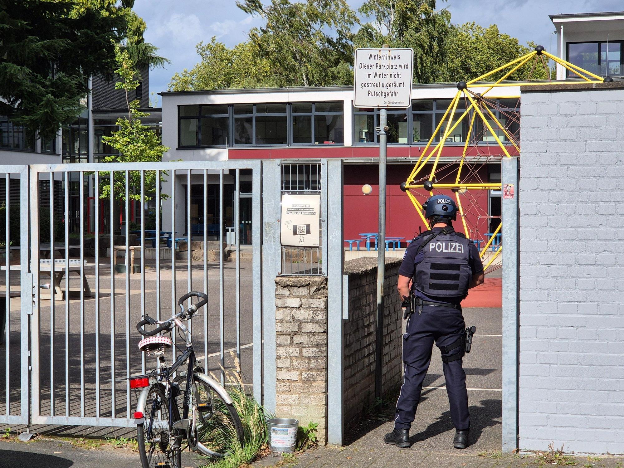 Ein Polizist steht vor einer Schule.