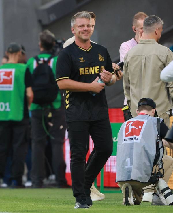 Lukas Kwasniok steht an der Seitenlinie und dreht eine Wasserflasche mit seinen Händen auf.