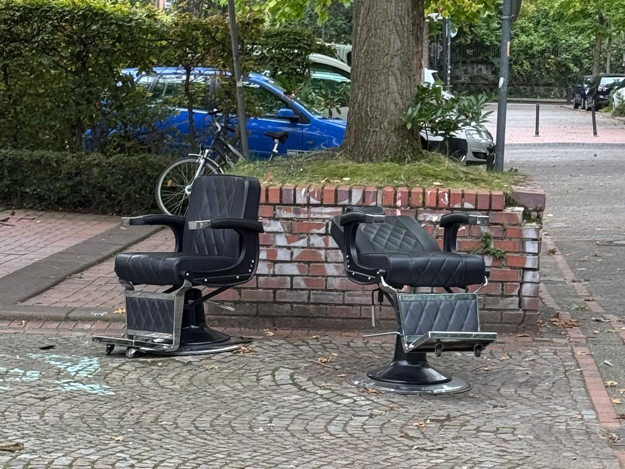 Zwei Stühle stehen an einer Straße.