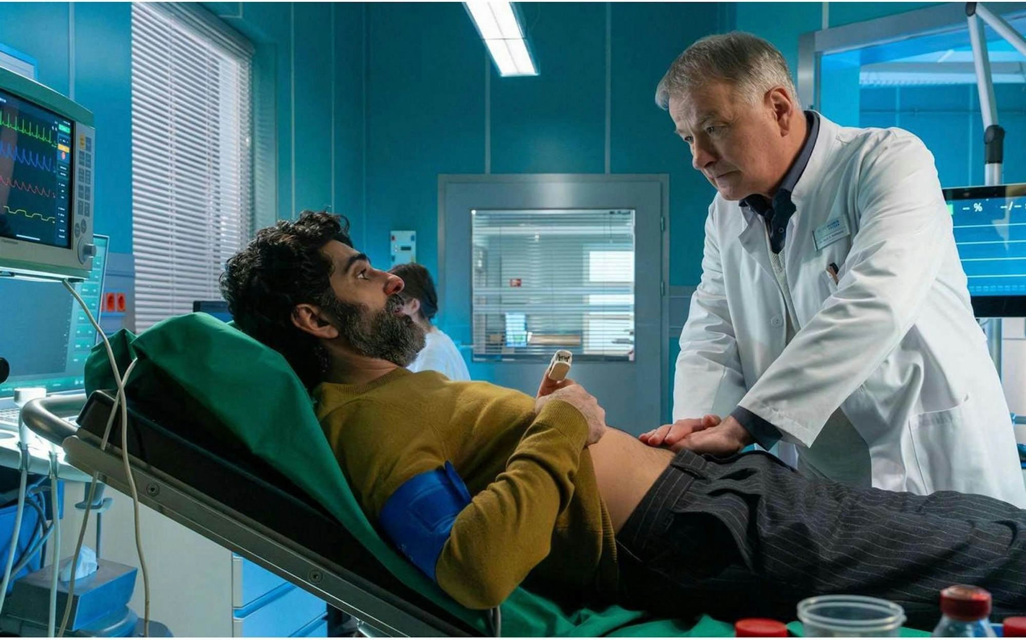 Dieser Fehler entrüstete die Fans von „In aller Freundschaft“: Dr. Heilmann (Thomas Rühmann) untersucht Razak Amari (Reza Brojerdi), trägt dabei aber nicht die Brille, die ihm gerade verordnet wurde. (Bild: MDR/Sebastian Kiss)