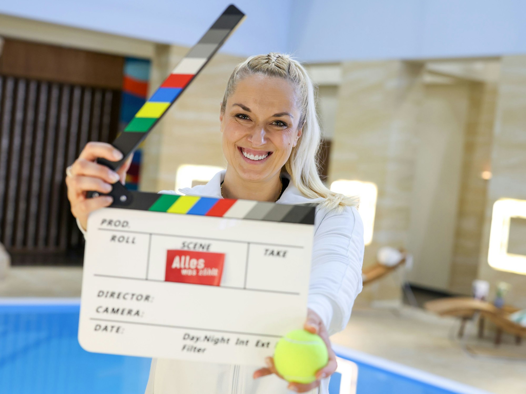 Sabine Lisicki steht mit einer Filmklappe im Filmset der RTL-Vorabendserie „Alles was zählt“.
