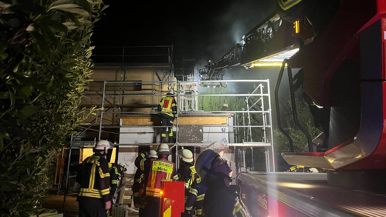 Feuerwehrleute sind nachts im Einsatz wegen eines brennenden Hauses.