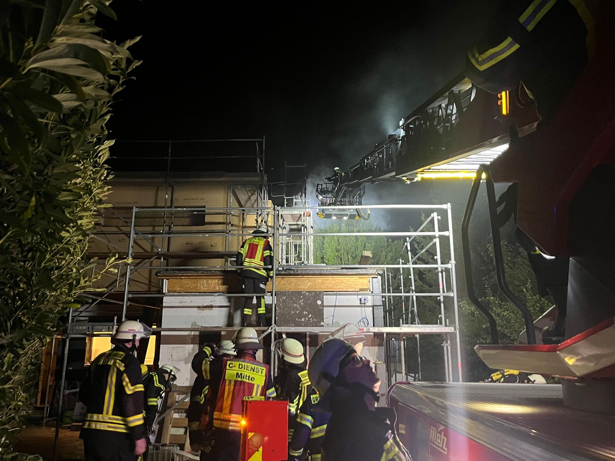 Feuerwehrleute sind nachts im Einsatz wegen eines brennenden Hauses.