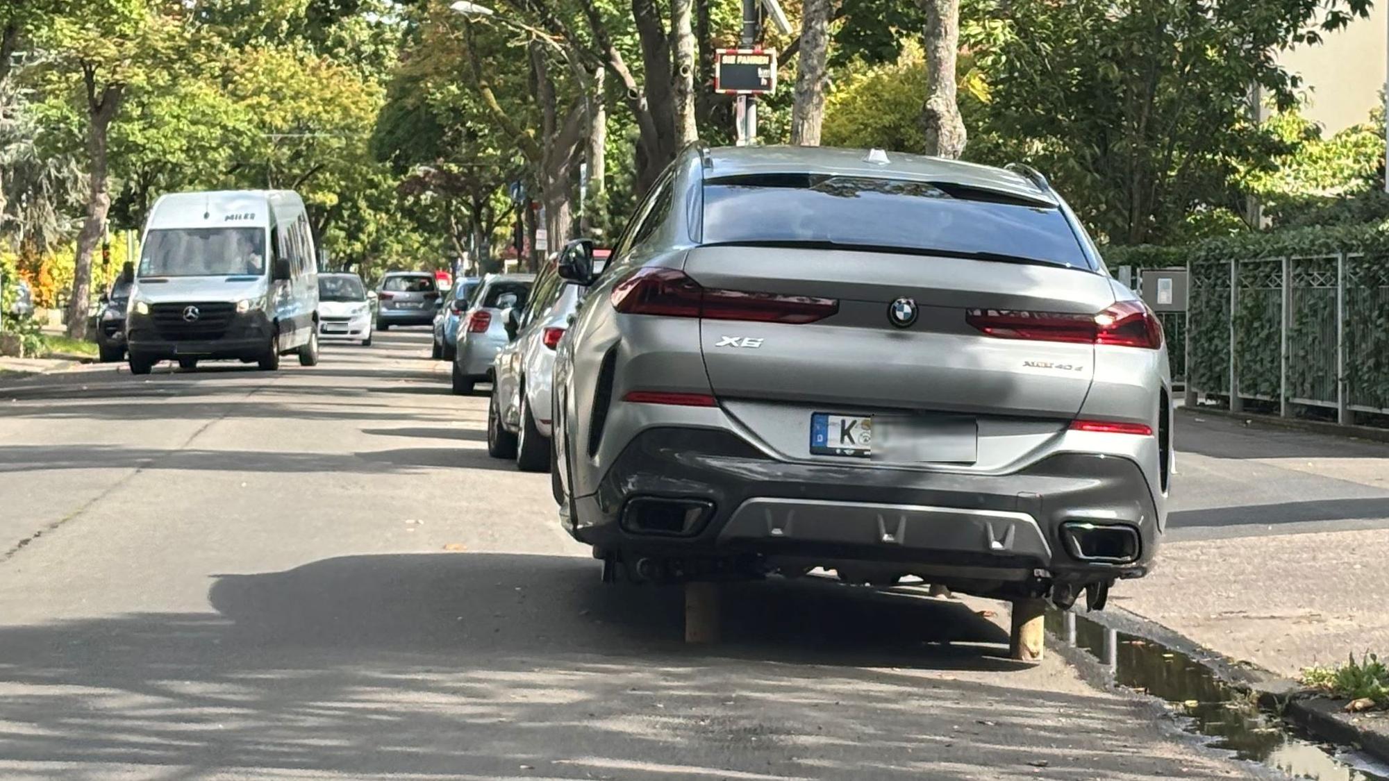 Ein Auto steht statt auf Rädern auf Holzpflöcken.