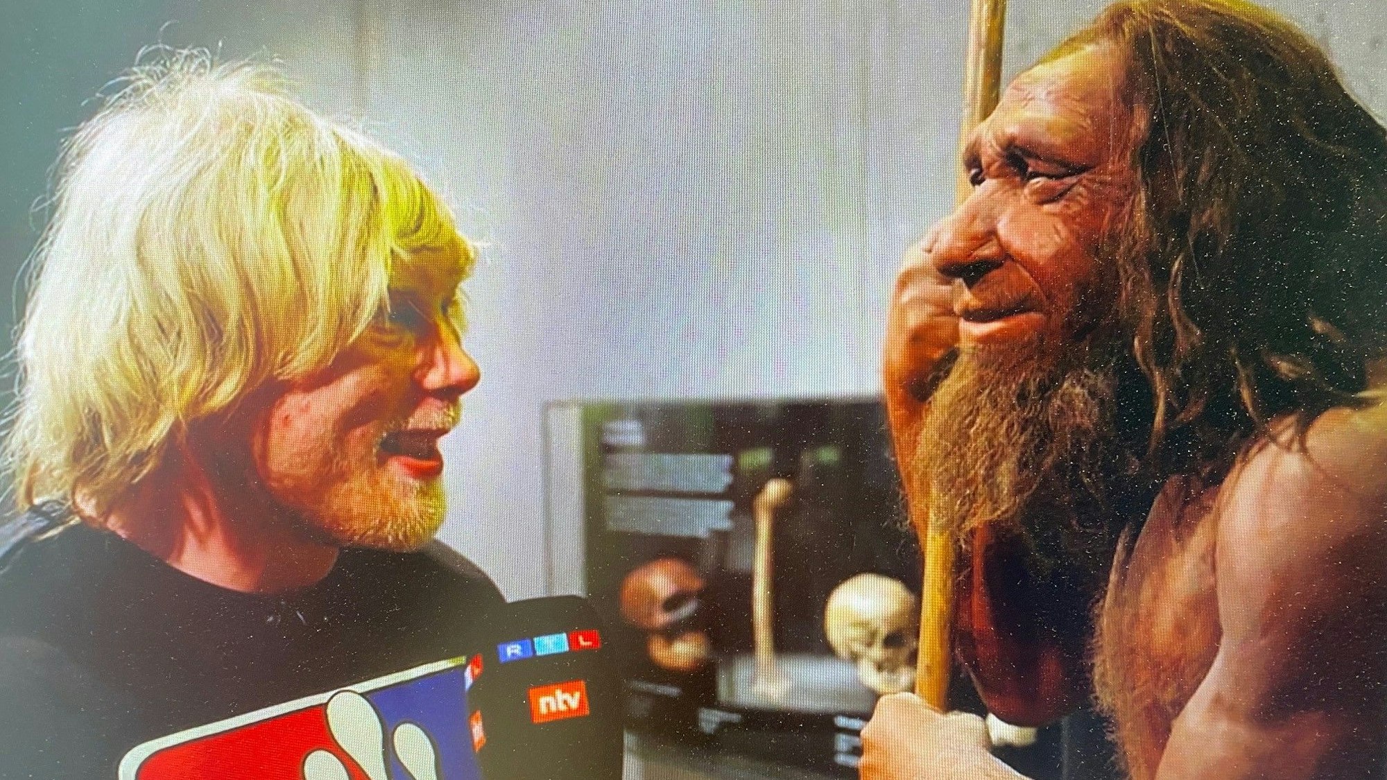 Ein Mann steht einer Neandertaler-Figur gegenüber.
