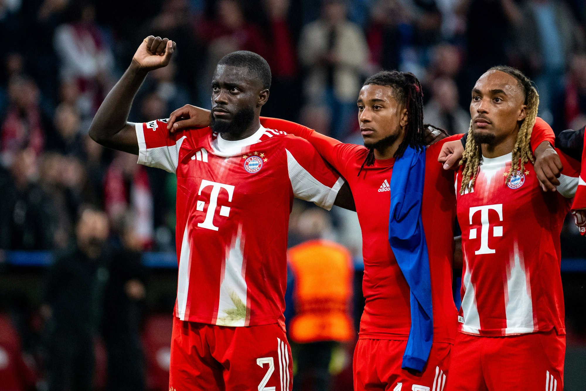 Dayot Upamecano, Michael Olise und Sacha Boey stehen vor der Bayern-Kurve.