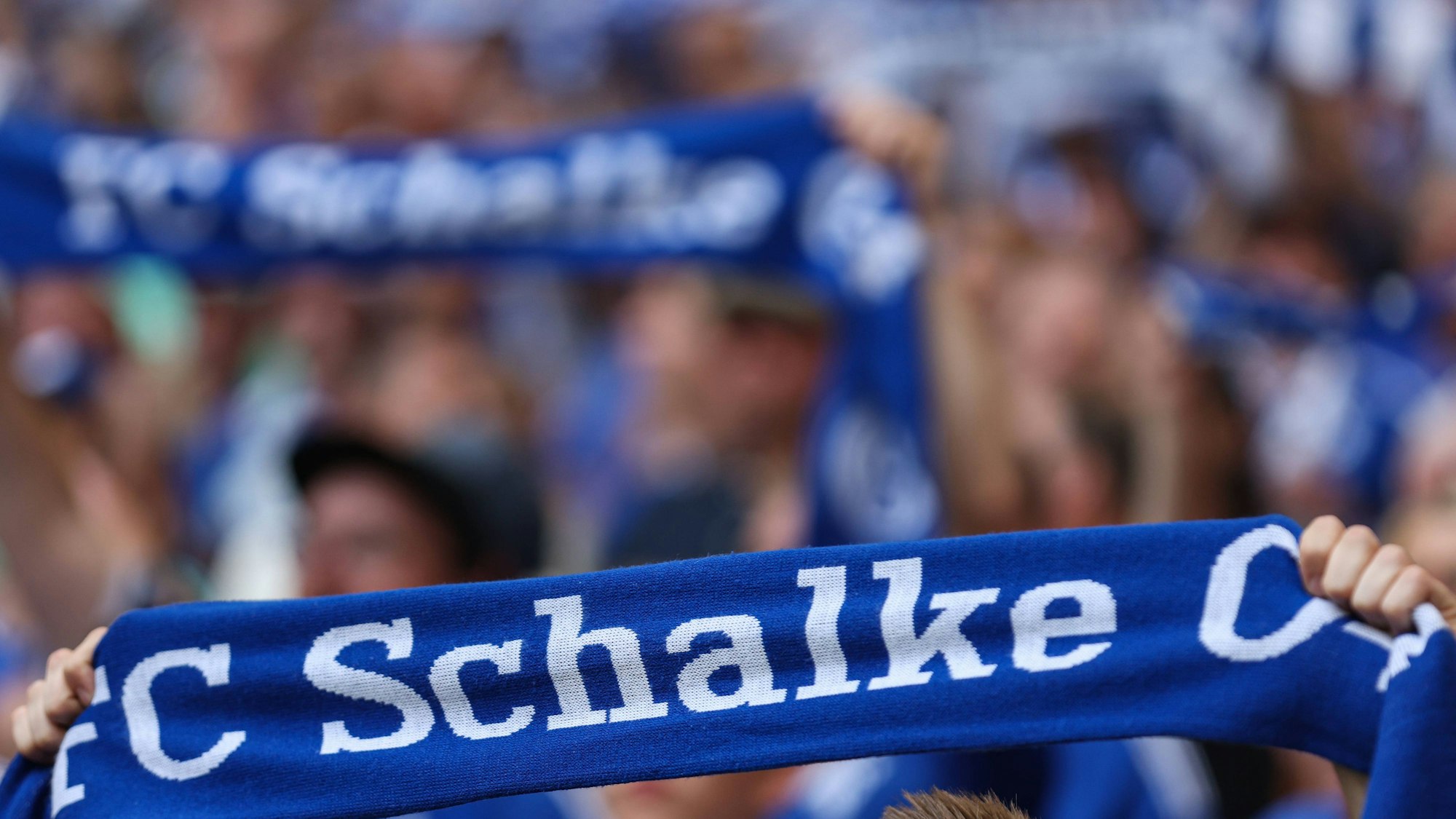 Hände halten einen Schalke-Fanschal hoch.