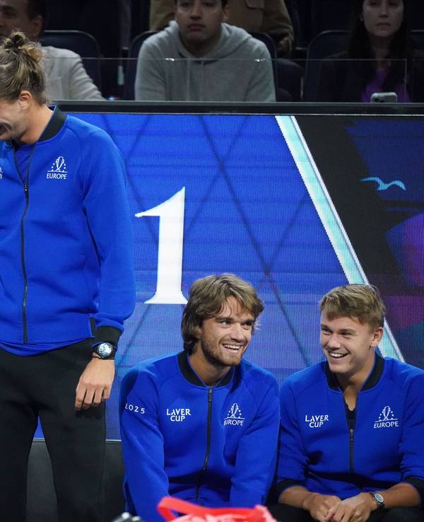 Alexander Zverev steht und streicht dem sitzenden Carlos Alcaraz mit der rechten Hand über den Kopf, beide lachen.