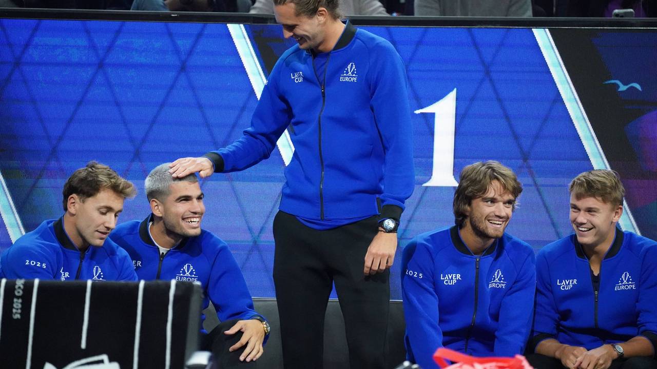 Alexander Zverev steht und streicht dem sitzenden Carlos Alcaraz mit der rechten Hand über den Kopf, beide lachen.