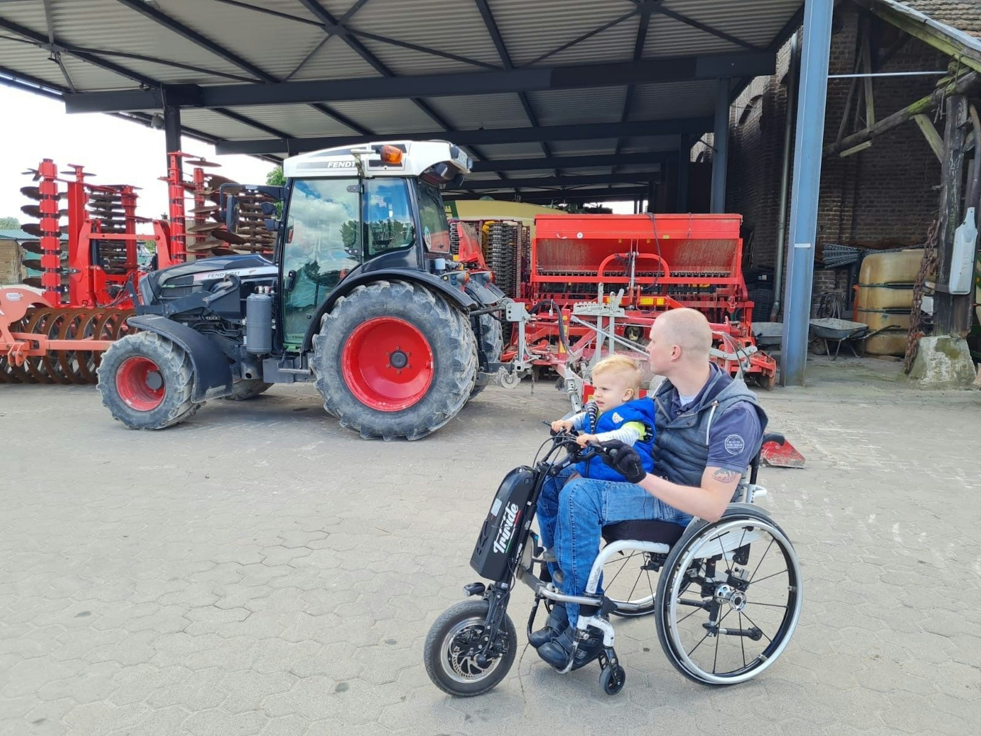 Ein Mann mit Kind im Rollstuhl auf einem Bauernhof