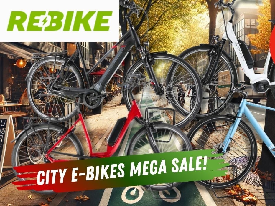 Mehrere City E-Bikes verschiedener Marken vor dem Hintergrund einer Innenstadt im Herbst.