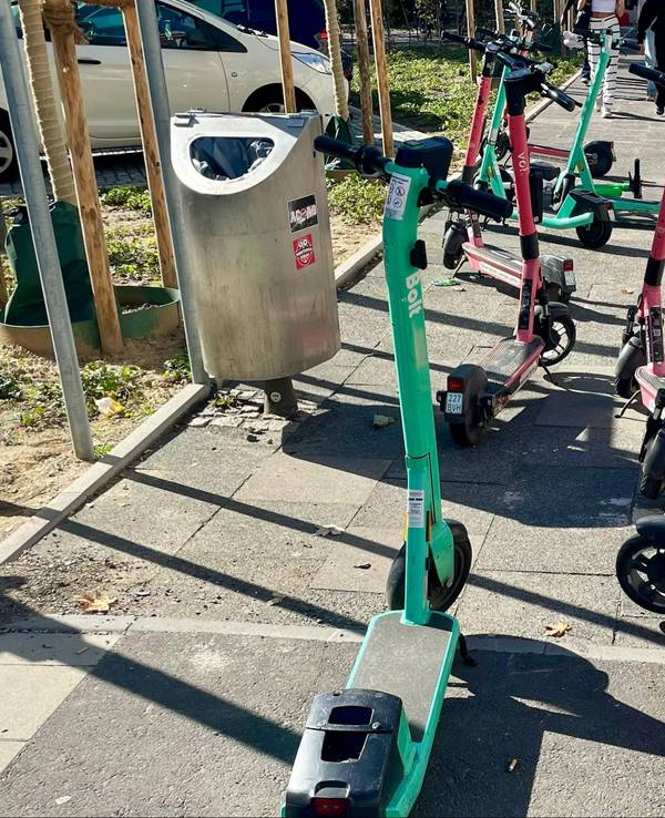E-Scooter stehen wild durcheinander auf einem Gehweg.