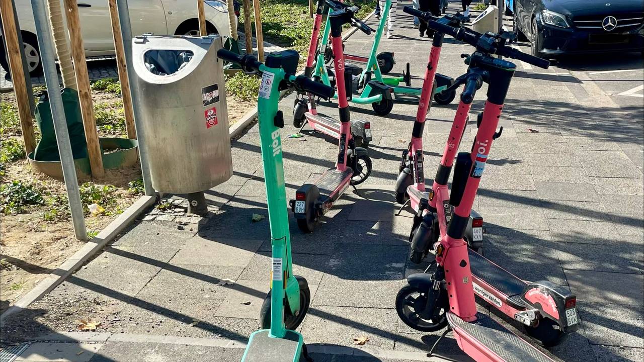 E-Scooter stehen wild durcheinander auf einem Gehweg.