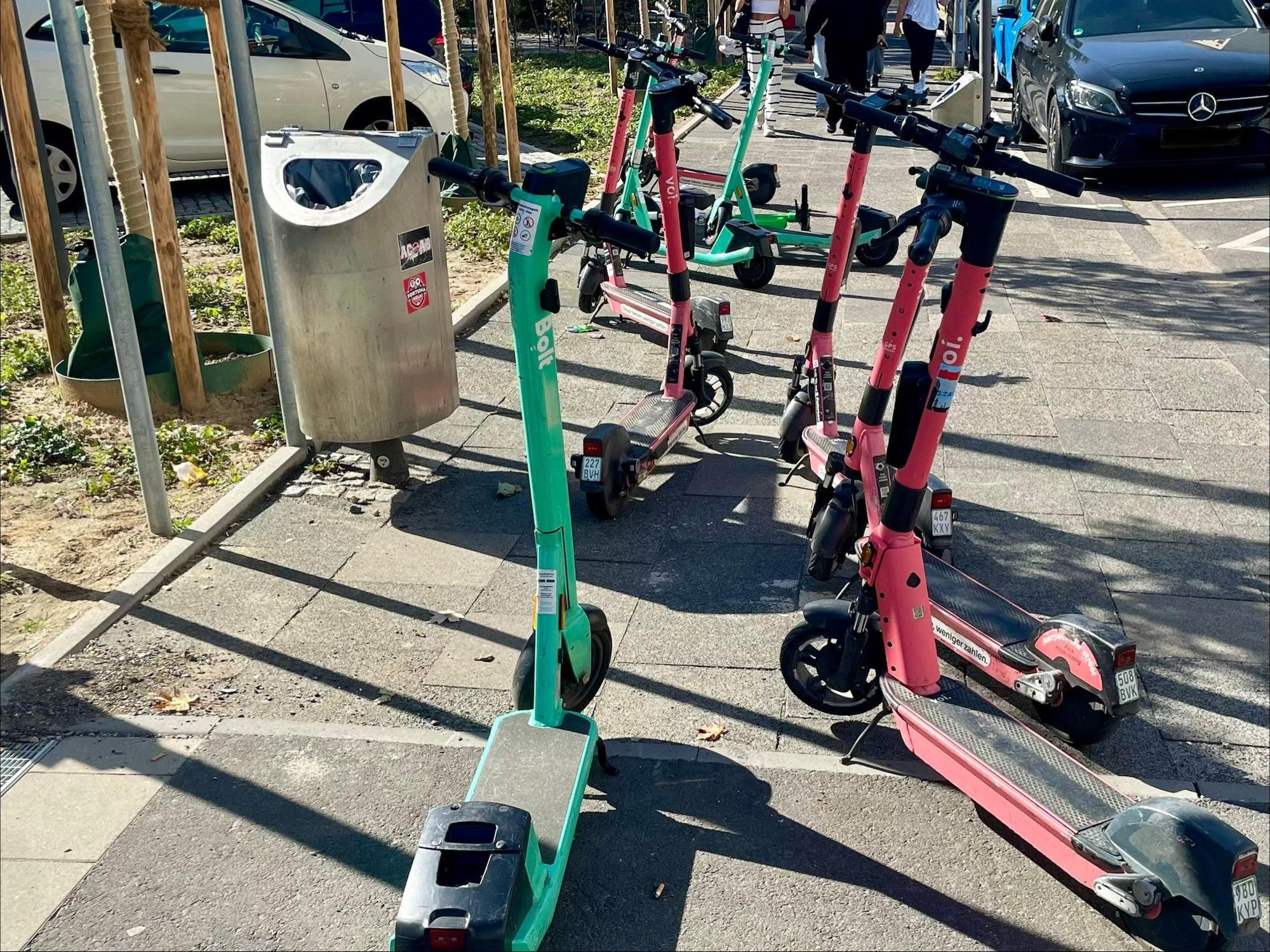 E-Scooter stehen wild durcheinander auf einem Gehweg.