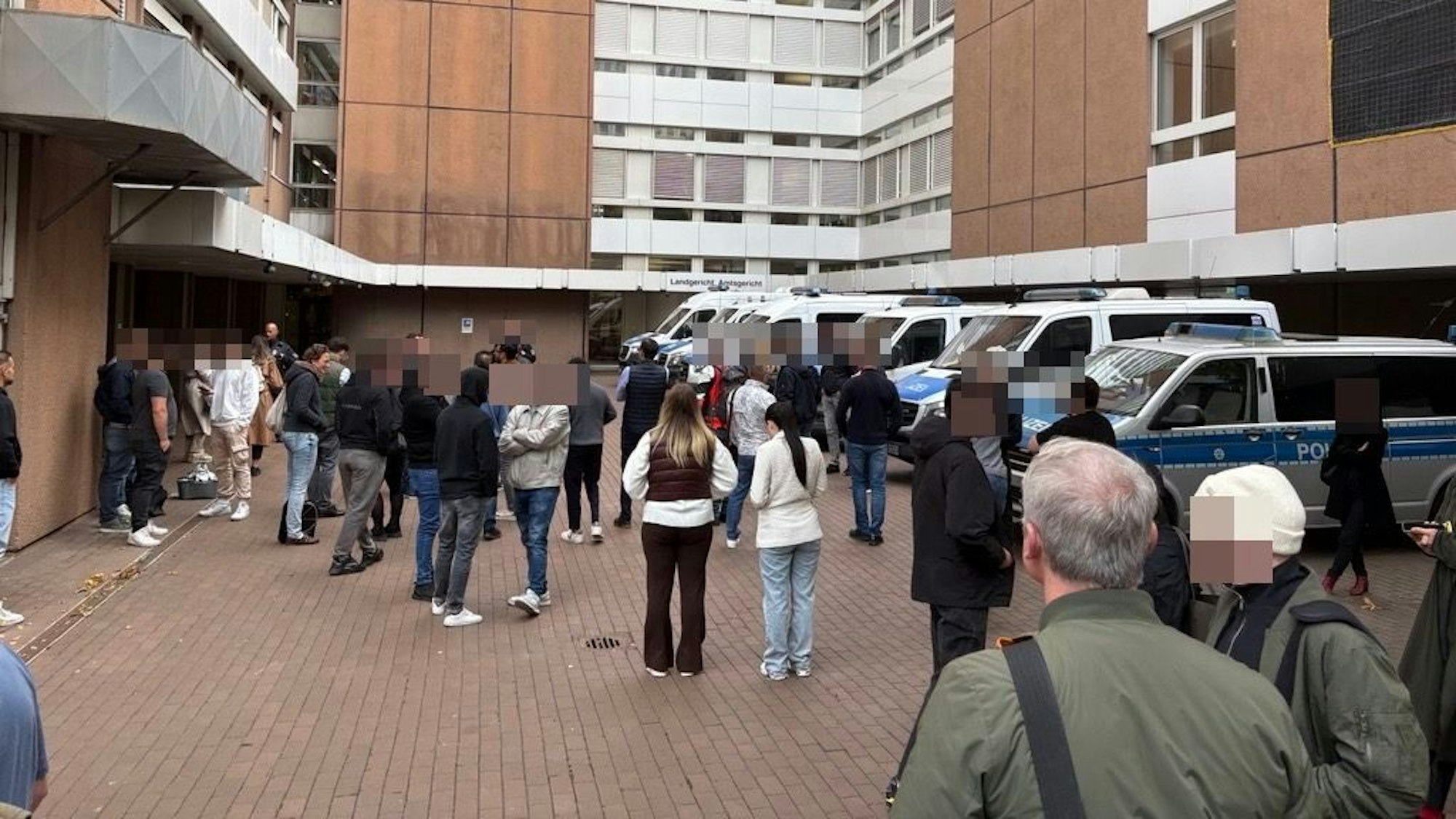 Menschen stehen vor dem geräumten Landgericht Köln.