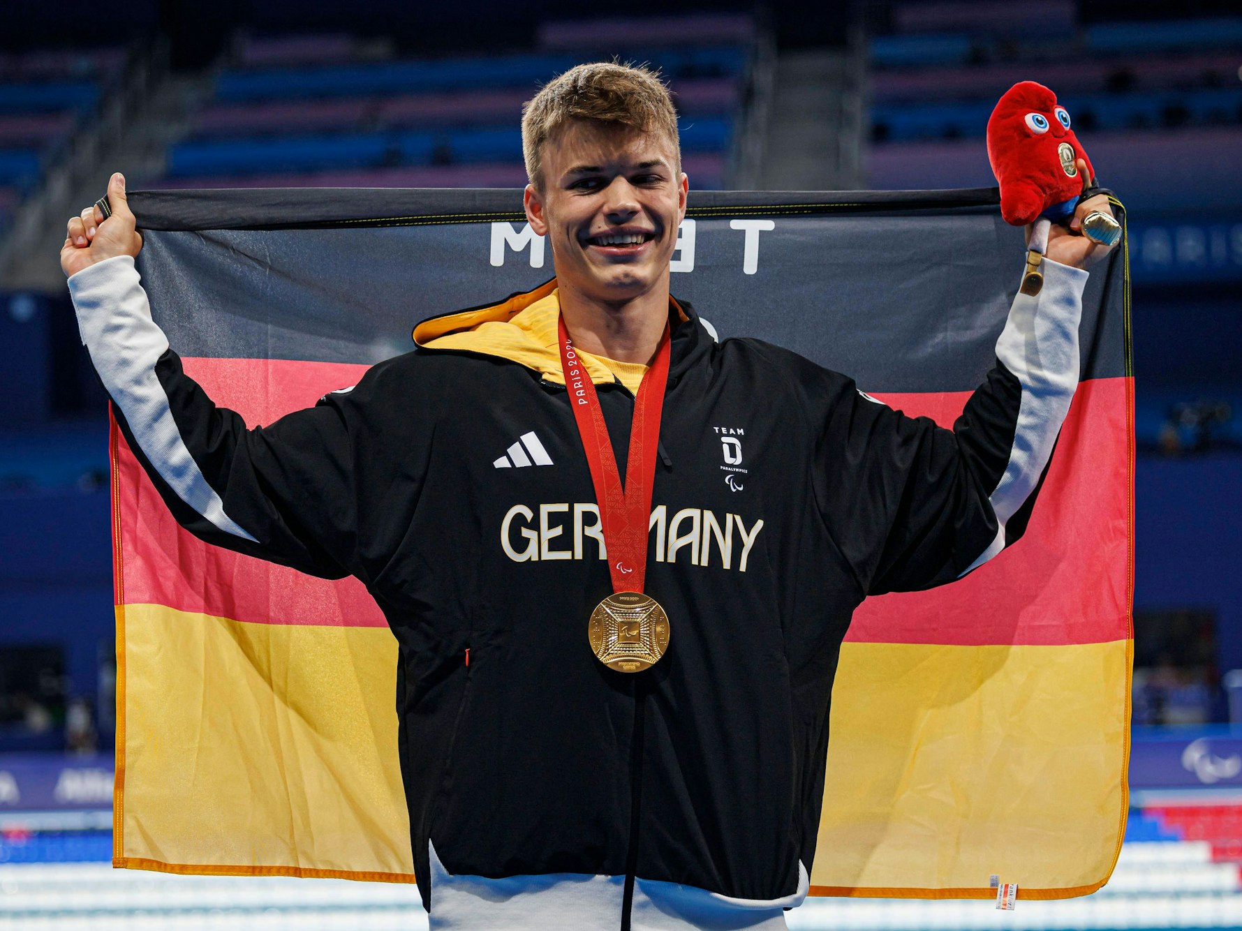 Taliso Engel hält die Deutschlandflagge hoch und hat die goldene Olympia-Medaille um.