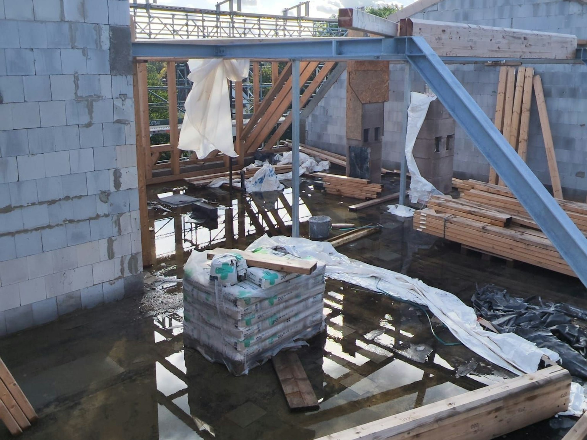 Das Dach des Hauses in Köln-Flittard fehlt, die Baustelle ist verwaist. Dicke Pfützen zeigen das Wasserproblem.