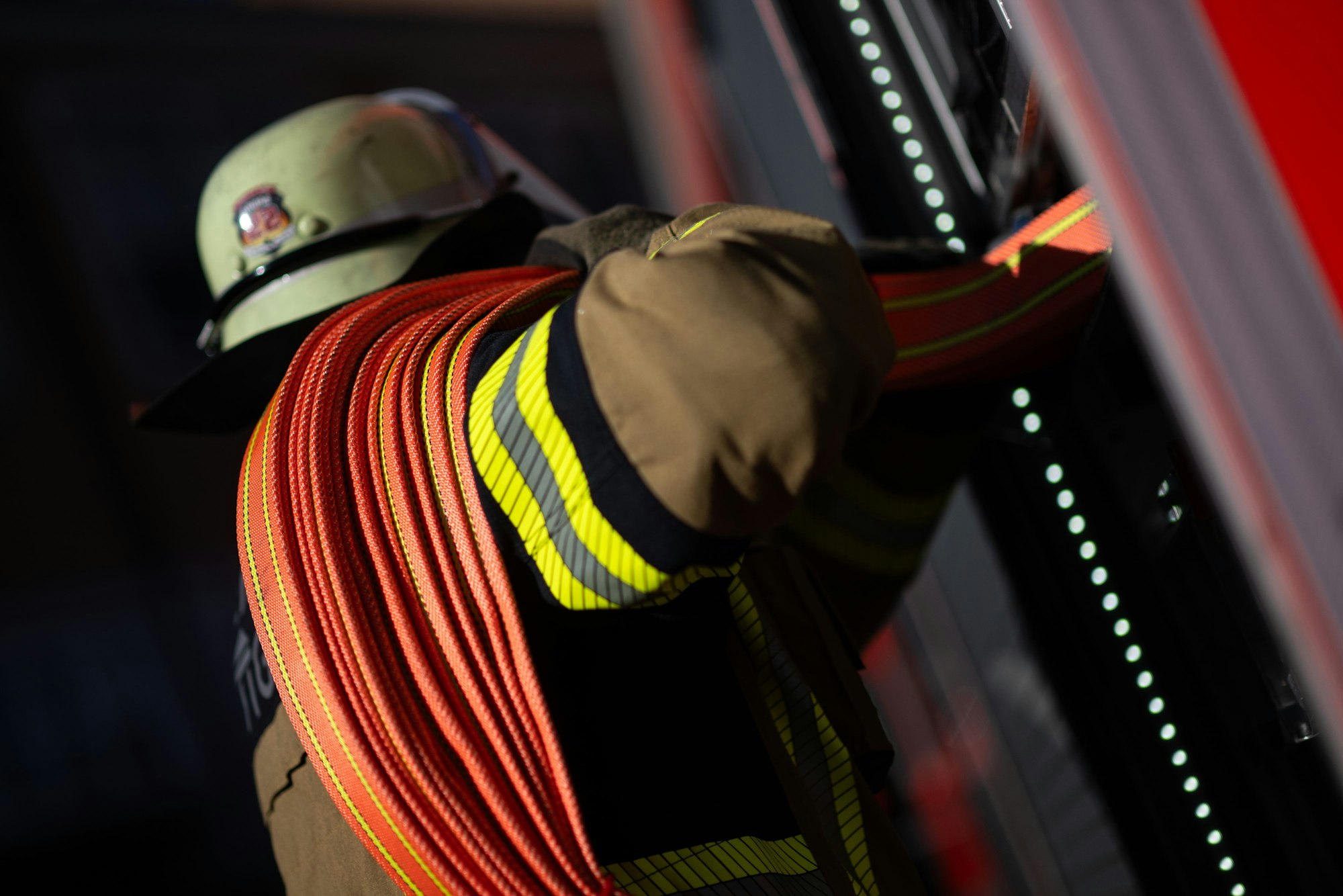 Eine Einsatzkraft der Feuerwehr nimmt einen Schlauch aus einem Einsatzfahrzeug.