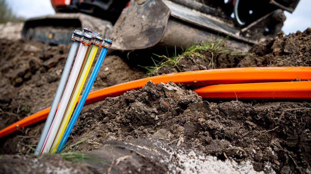 Glasfaser-Kabel liegen auf einer Baustelle, freigelegt von einem Bagger.