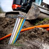Glasfaser-Kabel liegen auf einer Baustelle, freigelegt von einem Bagger.