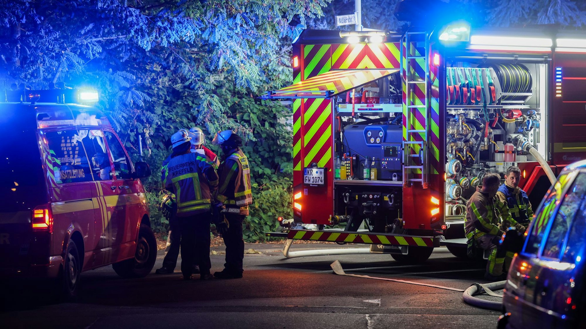 Mehrere Feuerwehrleute stehen an zwei Einsatzfahrzeugen.