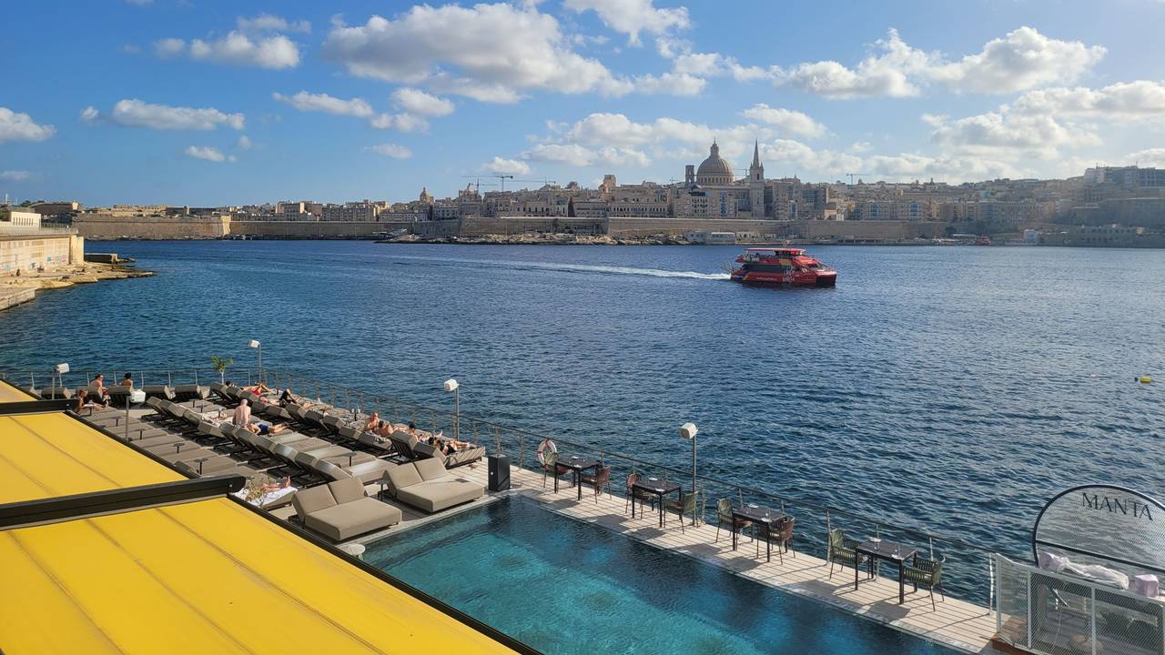 Ein Boot fährt auf einem Fluss vor der Skyline einer Stadt.