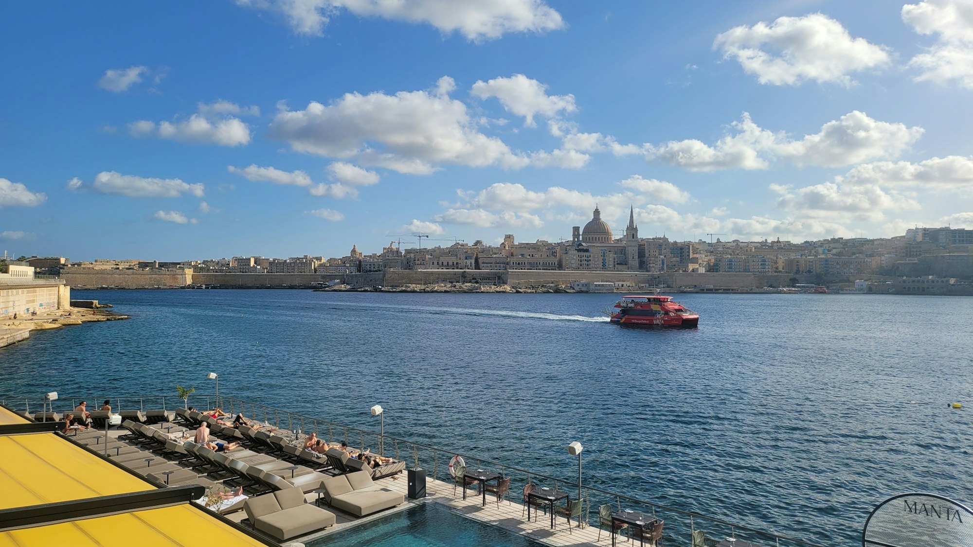 Ein Boot fährt auf einem Fluss vor der Skyline einer Stadt.